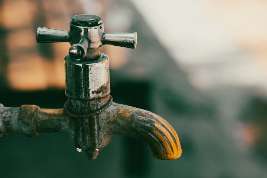 Detailed Close Up Of A Rustic Metal Faucet With Water Droplets, Perfect For Concepts Of Conservation And Decay.