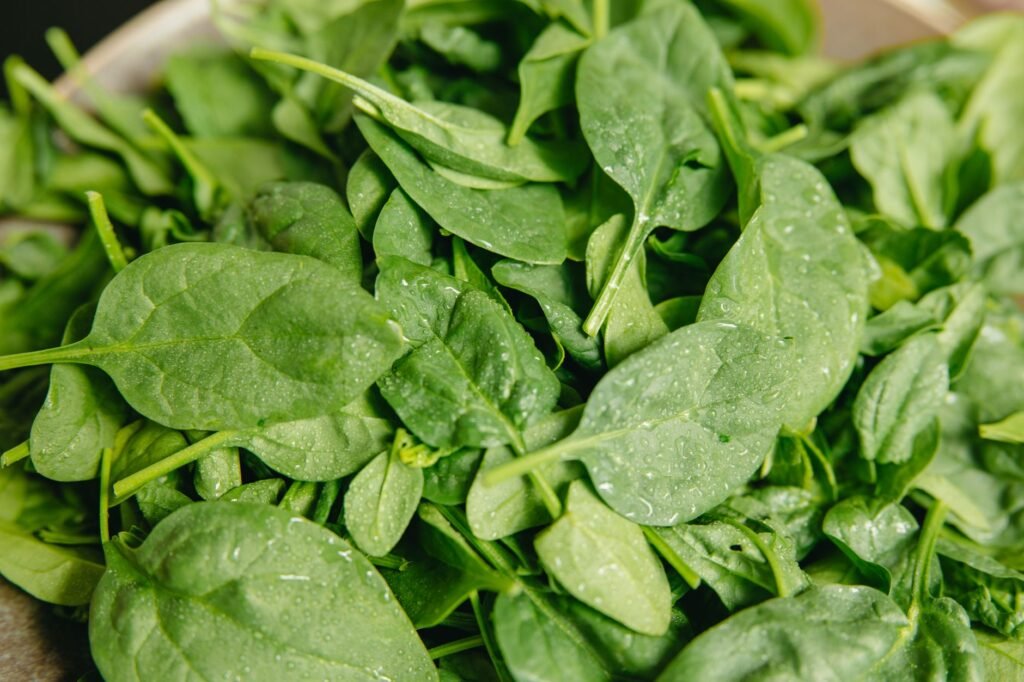 Close Up Of Fresh Spinach Leaves With Water Droplets, Highlighting Their Vibrant Green Color And Freshness.