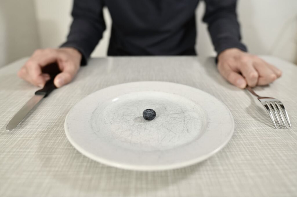 A Single Blueberry On A Scratched Plate Symbolizes Minimalist Diet And Portion Control.