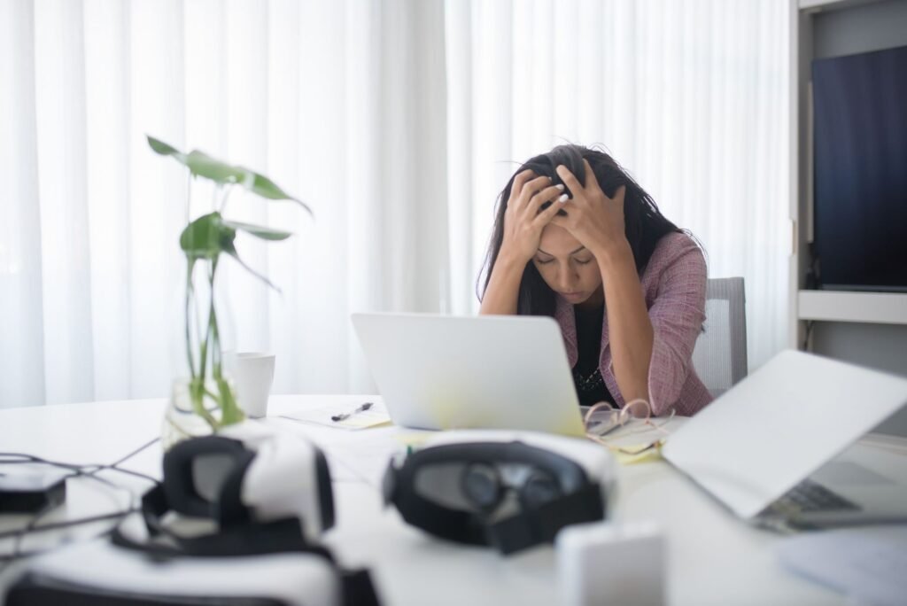 Frustrated Woman Sitting At Desk With Laptop, Showing Stress In A Modern Office Environment.